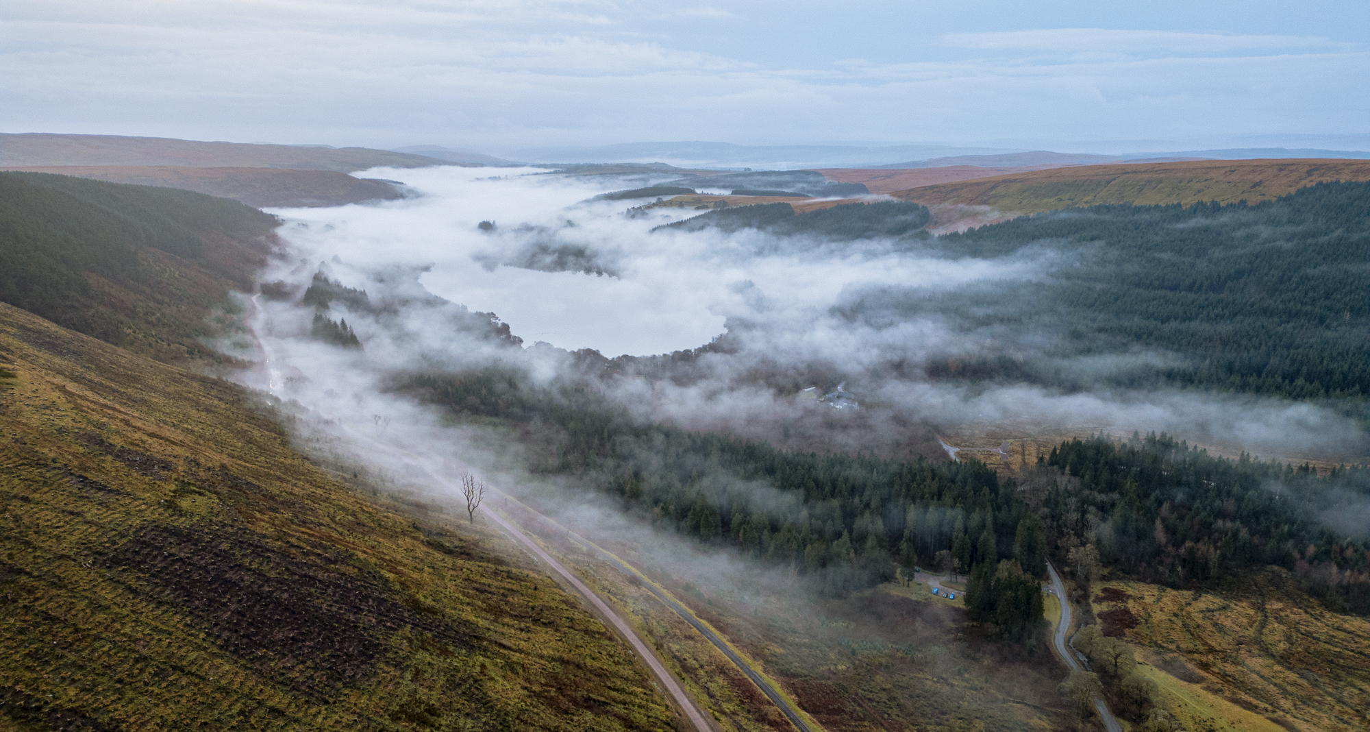 Brecon Beacons lakes under low cloud and mist at dawn.